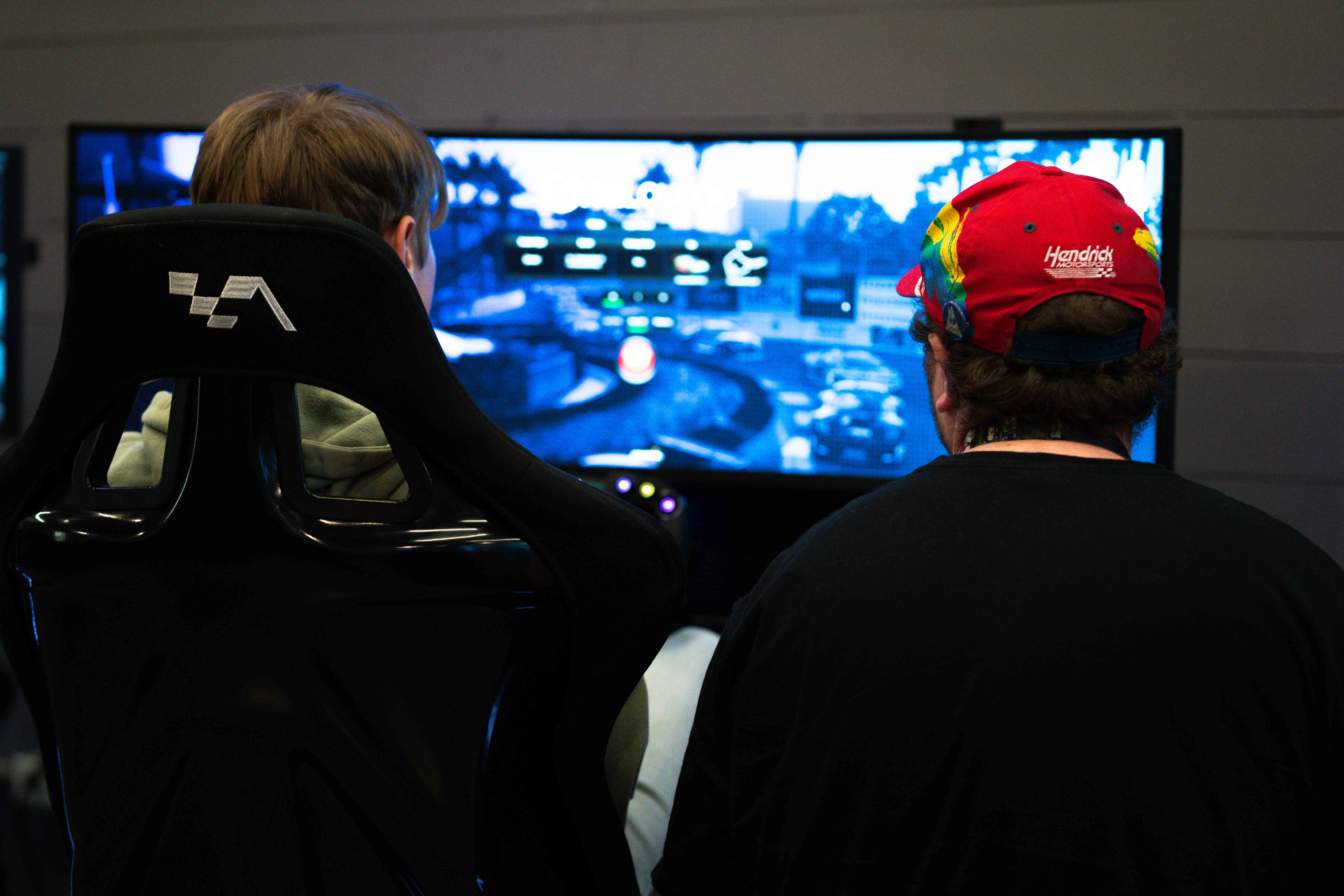 Two people seated at sim racing rigs side by side